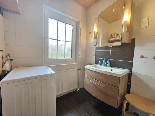 a white bathroom with a sink and a mirror at Ferienhaus Merlin in Norden