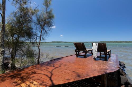 two chairs sitting on a wooden dock in the water at Eumarella Shores Noosa Lake Retreat in Noosaville