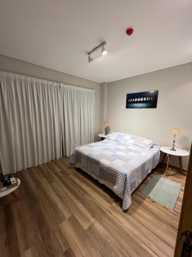 ein Schlafzimmer mit einem Bett und zwei Tischen in der Unterkunft Edificio El Arbol piso 2 in Corrientes