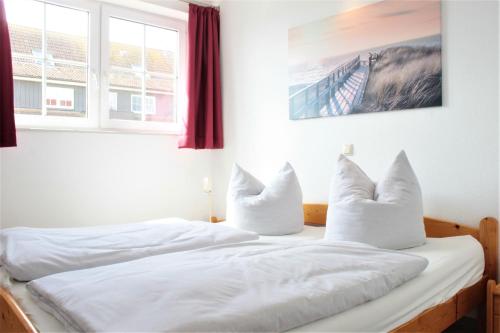 um quarto com 2 camas com lençóis brancos e almofadas em BreitlingBlicke em Gollwitz