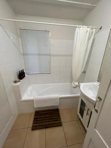 un bagno bianco con vasca e lavandino di Serenity on Stanthorpe a Fleurbaix
