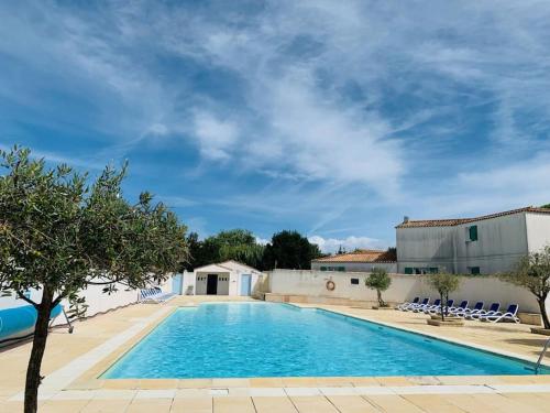 - une piscine dans un complexe avec des chaises et des arbres dans l'établissement La Voile Bleue de La Flotte, à La Flotte