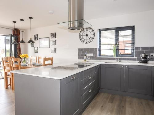 a kitchen with gray cabinets and a white counter top at The Hawthorns in Amlwch