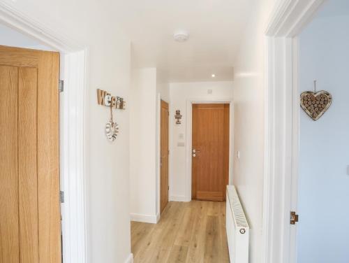 a hallway with white walls and a wooden door at The Hawthorns in Amlwch