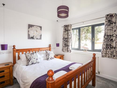 a bedroom with a wooden bed and windows at The Hawthorns in Amlwch