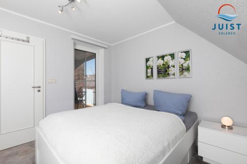 una camera da letto bianca con un letto con cuscini blu di Haus Hahntje 192 - Wohnung Sonnenwinkel a Juist