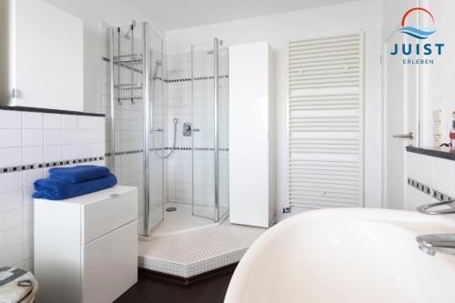 un bagno bianco con doccia e lavandino di Haus Hahntje 192 - Wohnung Sonnenwinkel a Juist