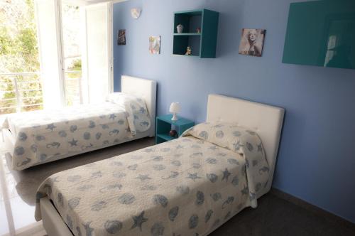 2 camas en una habitación con paredes azules en Case Vacanze Adelaide, en Cefalú