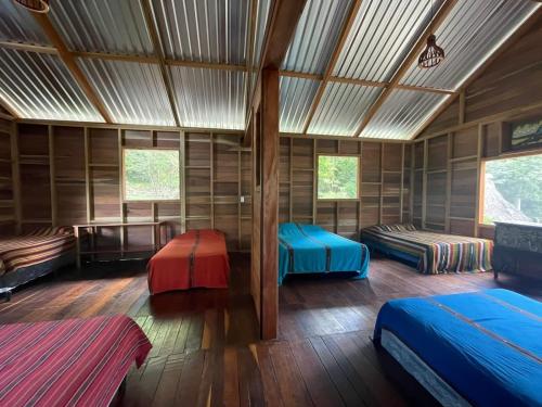 a room with three beds in a wooden room at Hotel Mon Ami in El Remate