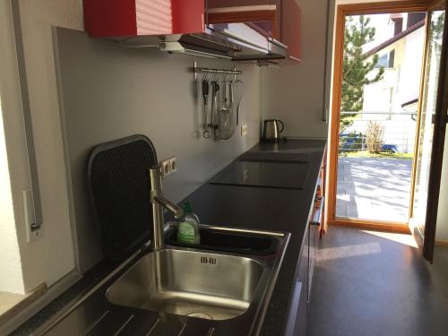 a kitchen with a stainless steel sink and a window at Ferienwohnung Blütenweg Kluftern in Friedrichshafen