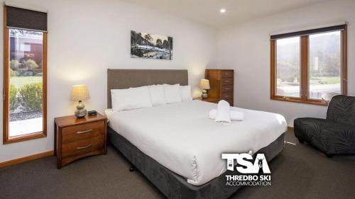 a bedroom with a large bed and a chair at Ski Fall at Lake Crackenback in Crackenback