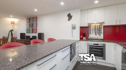 a kitchen with red and white cabinets and a counter at Ski Fall at Lake Crackenback in Crackenback