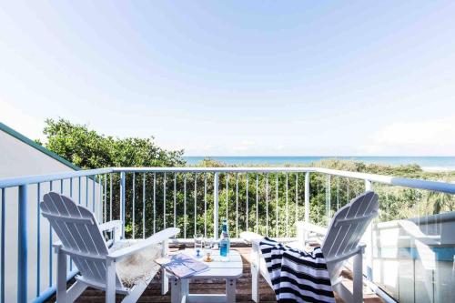 a patio with two chairs and a table on a balcony at Castaways Beach House Noosa in Marcus Beach