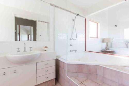 un bagno bianco con lavandino e specchio di Castaways Beach House Noosa a Marcus Beach