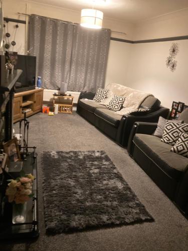 Guest House Chelsea في Halewood: غرفة معيشة بها أريكة وتلفزيون