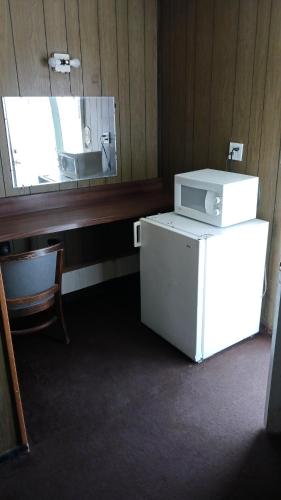 Habitación con nevera blanca y espejo. en White Pine Motel en Ely