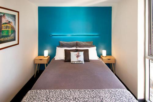 1 dormitorio con 1 cama grande y pared azul en Relaxing, light-filled city apartment, en Melbourne