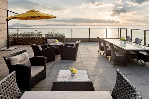 a patio with tables and chairs and an umbrella at Fairmont Yangcheng Lake in Kunshan