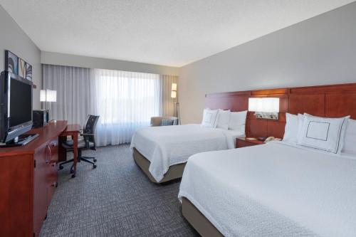 a hotel room with two beds and a flat screen tv at Courtyard Harlingen in Harlingen