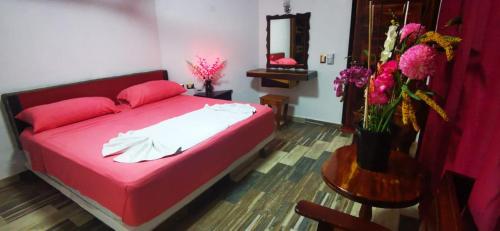 a bedroom with a red bed and a table with flowers at Casa CheJum Bacalar in Bacalar