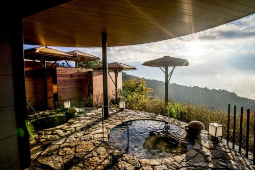 a patio with a pool of water and an umbrella at ANA InterContinental Beppu Resort & Spa by IHG in Beppu