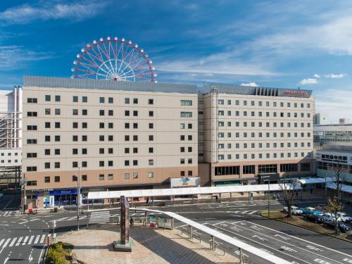 a large white building with a ferris wheel in the background at JR Kyushu Hotel Kagoshima in Kagoshima