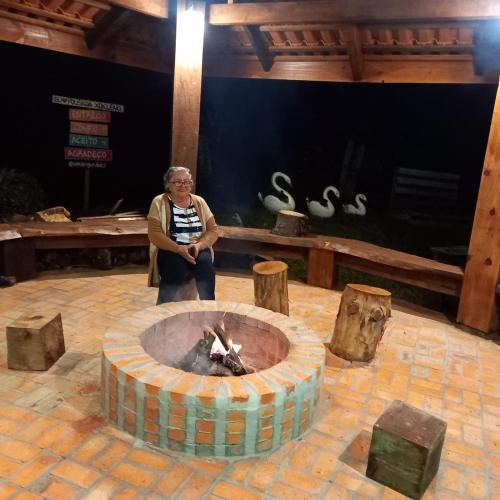 a woman standing in front of a fire pit at Pousada Cabanas Xokleng in Urubici
