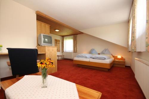 a room with a bed and a table with a vase of flowers at Pension Speckmoser in Bad Mitterndorf