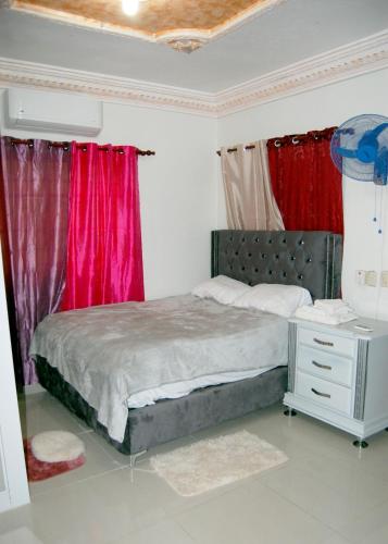 a bedroom with a bed with red curtains and a desk at Haabitacion Estudio III in Baní