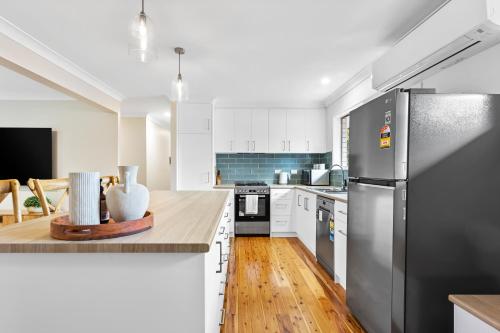 a kitchen with white cabinets and a stainless steel refrigerator at Maple Cottage - Perfect Eastside Location in Toowoomba