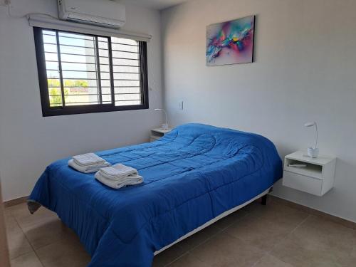 a bedroom with a bed with blue sheets and a window at MODERNO DUPLEX Con COCHERA in Luzuriaga