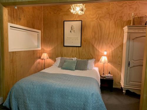 um quarto com uma cama com um cobertor azul e 2 candeeiros em BENROSE FARM COTTAGES em Wellington