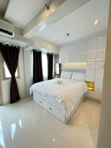 a bedroom with a white bed and a window at Coast Residences Penthouse with skyline and manila bay view in Manila