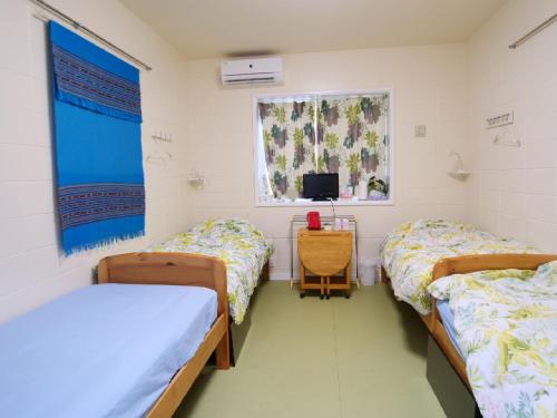 Pokój szpitalny z dwoma łóżkami i telewizorem w obiekcie Okinawa Resort w mieście Zamami