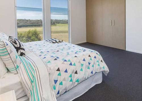 a bedroom with a bed and a large window at St Andrews Beach apartment 4 01 in Fingal