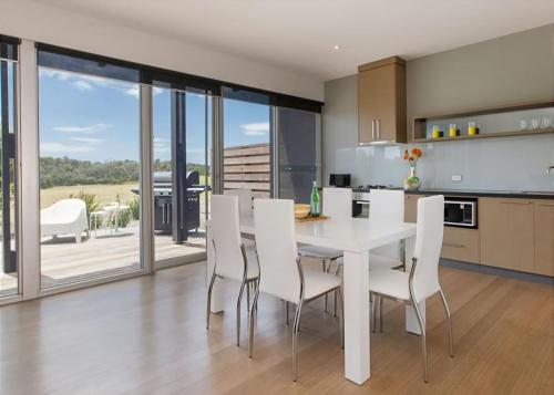 a kitchen and dining room with a white table and chairs at St Andrews Beach apartment 4 01 in Fingal
