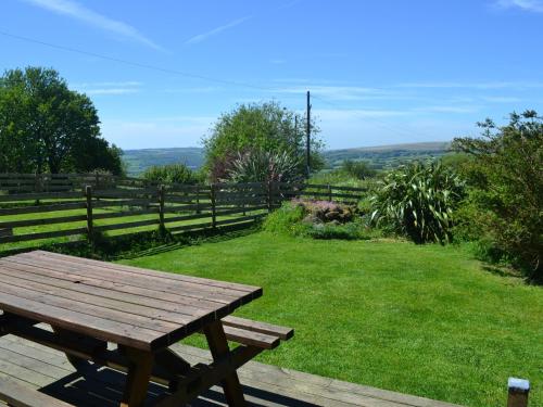 a wooden picnic table sitting in a field of grass at Nestling Barn in Marytavy
