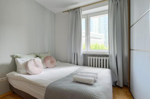 um quarto com uma cama com almofadas cor-de-rosa e uma janela em Jazz Residential Apart em Varsóvia