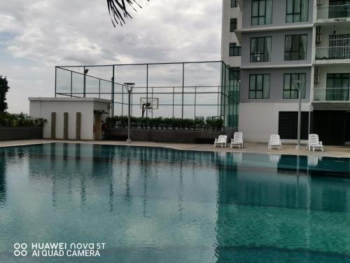 a swimming pool next to a building with a basketball court at Platino Aparment @ Paradigm Mall in Johor Bahru