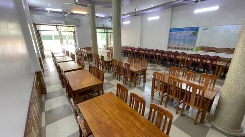 une salle de classe vide avec des tables et des chaises en bois dans l'établissement Sầm sơn star hotel, à Sầm Sơn