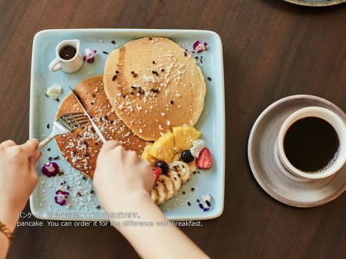 a child eating a plate of pancakes and a cup of coffee at First Cabin Nishi Umeda in Osaka