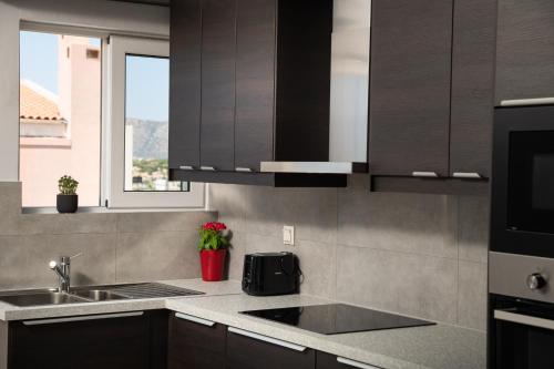 a kitchen with brown cabinets and a sink and a window at Procris Villas Breathtaking Sea View in Kalathas