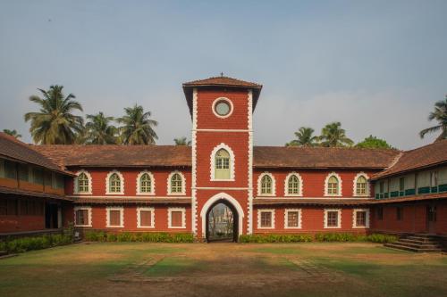 a large brick building with a clock tower at Sawantwadi Palace Boutique Art Hotel in Sawantwadi