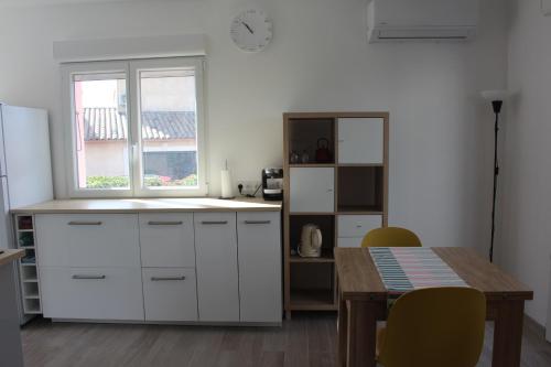 une cuisine avec des armoires blanches, une table et une fenêtre dans l'établissement Le Beau site by Beds83, à Fréjus