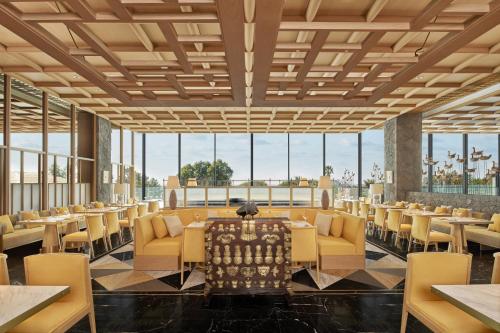 a dining room with tables and chairs and large windows at JW Marriott Jeju Resort & Spa in Seogwipo