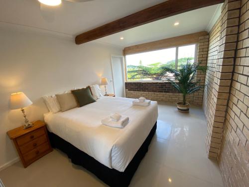 sypialnia z dużym białym łóżkiem i oknem w obiekcie Wave Cave Suite w mieście Coffs Harbour