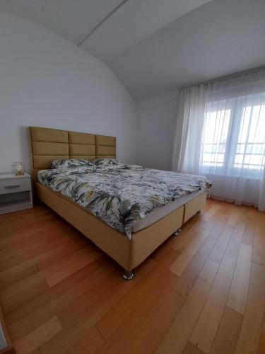Bett in einem Schlafzimmer mit Holzboden in der Unterkunft Apartman Lena in Banja Luka
