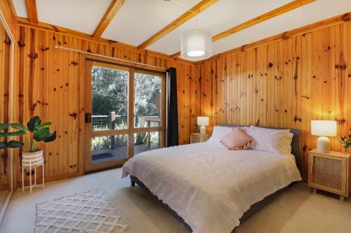 een slaapkamer met een bed en een groot raam bij Woodland Rise in Mount Buller