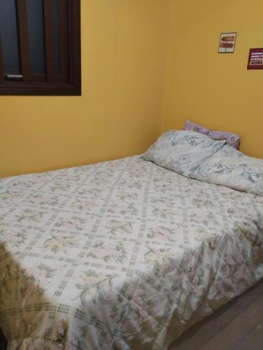 a bedroom with a bed with a comforter on it at Pousada Atlântica stay home in Tramandaí