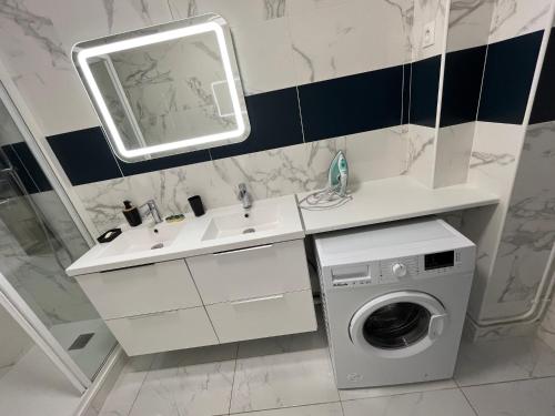 ein Badezimmer mit einer Waschmaschine und einem Waschbecken in der Unterkunft Appartement Prestige - Amiens in Amiens
